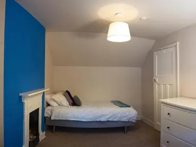 a small bedroom with a bed and a blue wall at Chapel House Cottage in Builth Wells