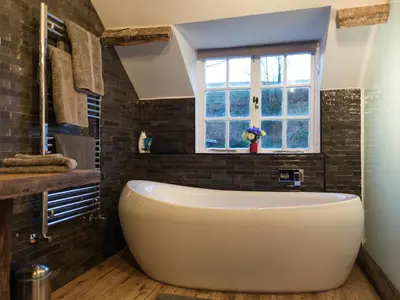 a large white tub in a bathroom with a window at Chapel House Cottage in Builth Wells