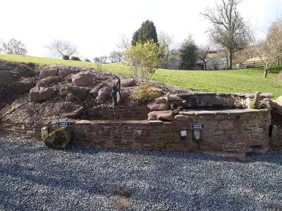 a stone retaining wall with a fountain in a yard at The Draen Bed and Breakfast in Brecon