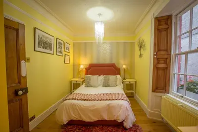 a bedroom with a bed with yellow walls and a window at The Drovers Bed and Breakfast in Llandovery