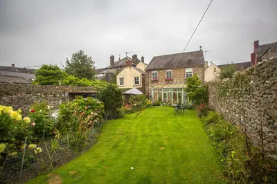 a yard with a stone wall and a house at The Drovers Bed and Breakfast in Llandovery