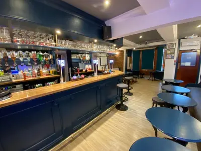a bar with blue walls and tables and bar stools at Plas Coch Hotel Ltd in Bala