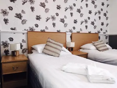 two beds in a bedroom with flowers on the wall at Plas Coch Hotel Ltd in Bala