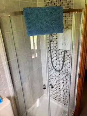 a shower in a bathroom with a blue towel at Nant-Y-Glyn in Llandrindod Wells