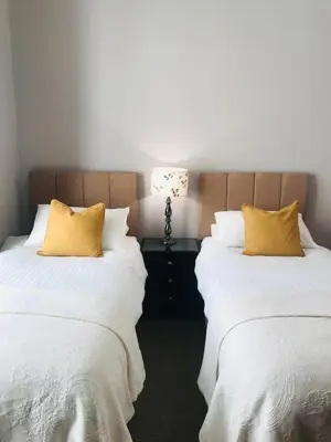 two beds with white sheets and yellow pillows in a room at Endeavour Guest House in Barmouth
