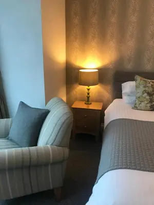 a hotel room with a couch and a bed and a lamp at Endeavour Guest House in Barmouth