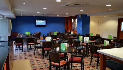 a dining room with tables and chairs and a blue wall at Holiday Inn Express Shrewsbury by IHG in Shrewsbury