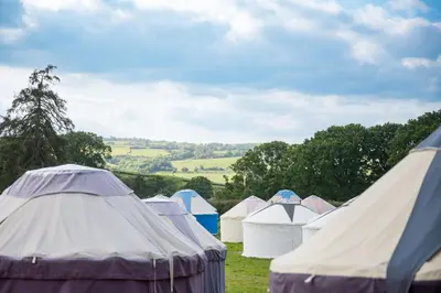 a group of tents in a field with trees at Festival Yurts Hay-on-Wye in Hay-on-Wye