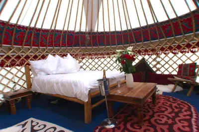 a bedroom in a yurt with a bed and a table at Festival Yurts Hay-on-Wye in Hay-on-Wye