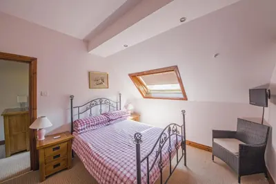 a bedroom with a bed and a chair at Llanerchindda Farm Guest House in Cynghordy
