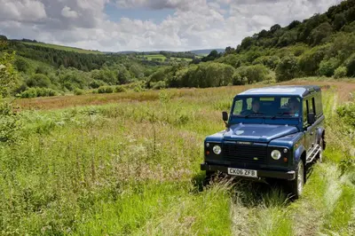 a blue truck driving through a field of grass at Llanerchindda Farm Guest House in Cynghordy