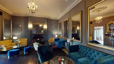 a living room with blue furniture and a fireplace at Peterstone Court Country House Restaurant & Spa in Brecon
