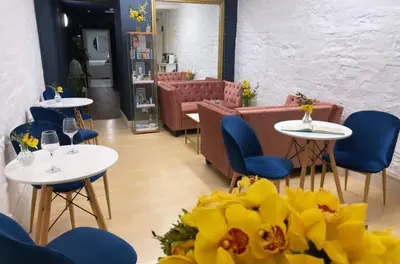 a restaurant with white tables and blue chairs and yellow flowers at Peterstone Court Country House Restaurant & Spa in Brecon