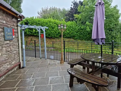 a picnic table with an umbrella next to a fence at Castle Lodge - Brecon Beacons Accommodation in Sennybridge