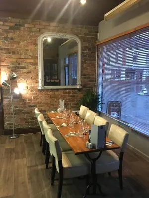 a dining room with a table with chairs and a brick wall at Ty Morgan's in Rhayader