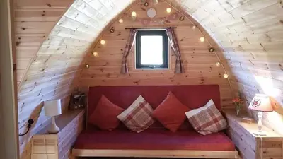 a red couch in a wooden room with a window at Bwlcheinion Sea View Glamping in Machynlleth
