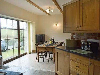 a kitchen with a table with chairs and a large window at Ty Nant in Llanon