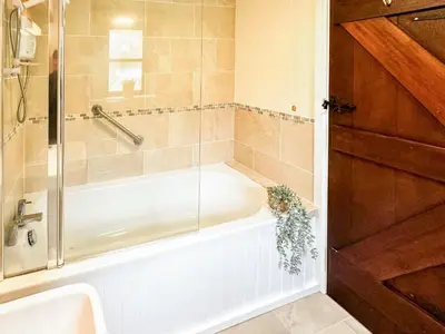 a bath tub with a glass shower door next to a sink at Kite 1 - Uk6549 in Llanfihangel-Bryn-Pabuan