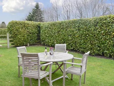 a table with four chairs and a bottle of wine at Acorn Cottage in Kingsland