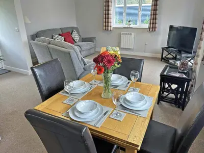 a dining room table with a vase of flowers on it at Acorn Cottage in Kingsland
