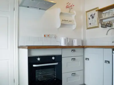 a kitchen with white cabinets and a black oven at The Cider Barn in Presteigne