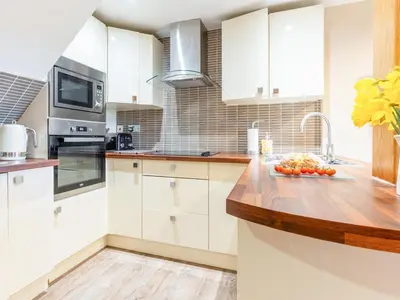 a kitchen with white cabinets and a wooden counter top at Ty Bach Twt in Dyffryn
