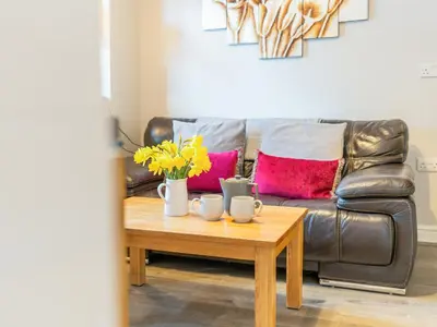 a living room with a leather couch and a coffee table at Bwthyn Bach in Dyffryn