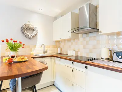 a kitchen with white cabinets and a wooden table at Bwthyn Bach in Dyffryn