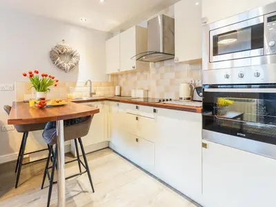 a kitchen with white cabinets and a wooden table at Bwthyn Bach in Dyffryn