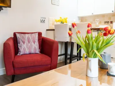 a living room with a red chair and a table with flowers at Bwthyn Clyd in Dyffryn