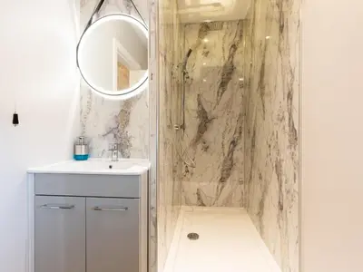 a bathroom with a shower with a sink and a mirror at Bwthyn Clyd in Dyffryn