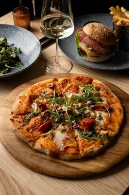a pizza on a table with a sandwich and a glass of wine at Penrhos Park in Aberystwyth