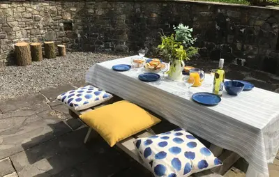 a table with blue and white plates and bottles and chairs at Cae'r Beili in Llandovery