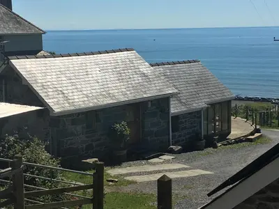 a stone house with the ocean in the background at Beautiful Wales in Barmouth