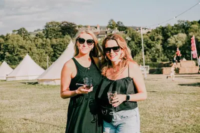 two women standing next to each other holding wine glasses at Glamping at Hay Festival in Hay-on-Wye