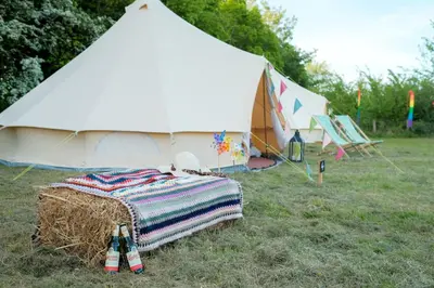 a bed in a field next to a tent at Glamping at Hay Festival in Hay-on-Wye