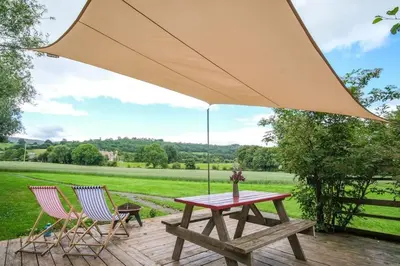 a picnic table with two chairs and a large umbrella at Wye Glamping in Velindre