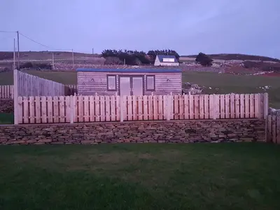 a wooden fence in front of a house at Allibella Shepherds Hut, Amazing Seaview, Private garden, Pet Friendly in Barmouth