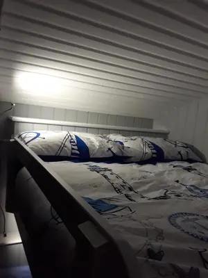 a bed with white sheets and pillows on it at Allibella Shepherds Hut, Amazing Seaview, Private garden, Pet Friendly in Barmouth