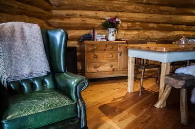 a green leather chair in a room with a table at Coed y Marchog Woodland Retreat in Hereford