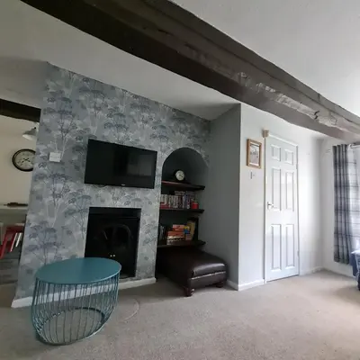 a living room with a fireplace and a flat screen tv at Abbey Cottage in Shrewsbury