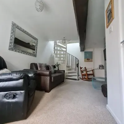 a living room with a leather couch and a staircase at Abbey Cottage in Shrewsbury