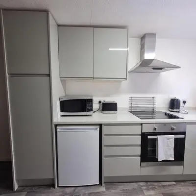 a kitchen with white cabinets and a stove and refrigerator at Abbey Cottage in Shrewsbury