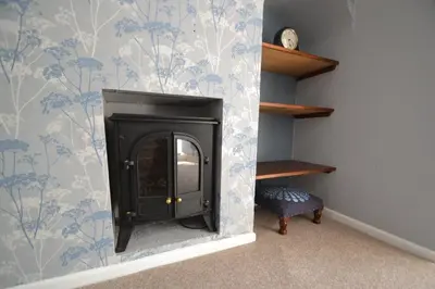 a fireplace in a room with blue and white wallpaper at Abbey Cottage in Shrewsbury