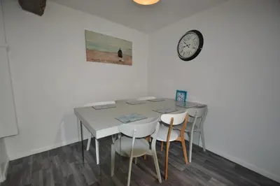 a dining room table with chairs and a clock on the wall at Abbey Cottage in Shrewsbury