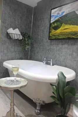 a bathroom with a white tub and a glass of wine at The Coach House Brecon in Brecon