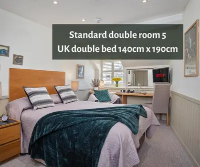 a bedroom with a large bed and a kitchen at The Coach House Brecon in Brecon
