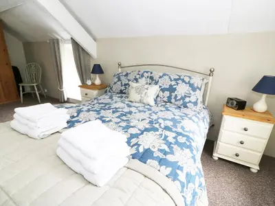 a bedroom with a blue and white bed with towels on it at Penglanowen Fawr in Rhostie