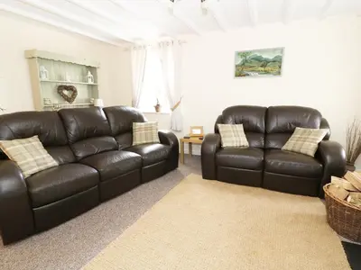 a living room with two leather couches and a table at Penglanowen Fawr in Rhostie