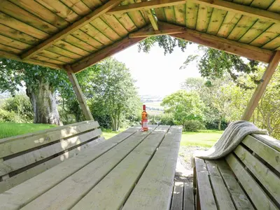 a wooden picnic table with two benches in a park at Penuwch Fach in Llanfihangel-y-creuddyn